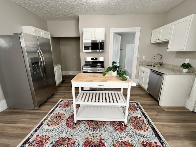 626 W 12th St, Covington, KY 41011 - kitchen with stainless steel appliances, white cabinets, dark wood-style floors, and a textured ceiling