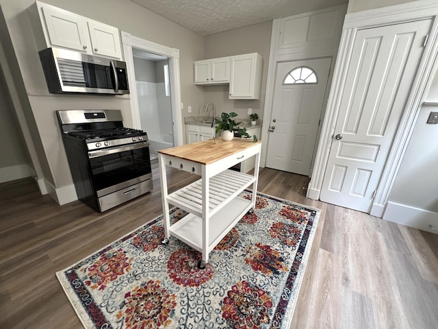 626 W 12th St, Covington, KY 41011 - kitchen featuring appliances with stainless steel finishes, white cabinetry, light countertops, dark wood-style floors, and a textured ceiling
