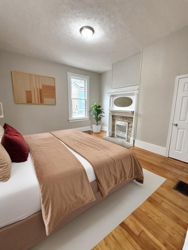 626 W 12th St, Covington, KY 41011 - bedroom with wood finished floors, a textured ceiling, and a fireplace