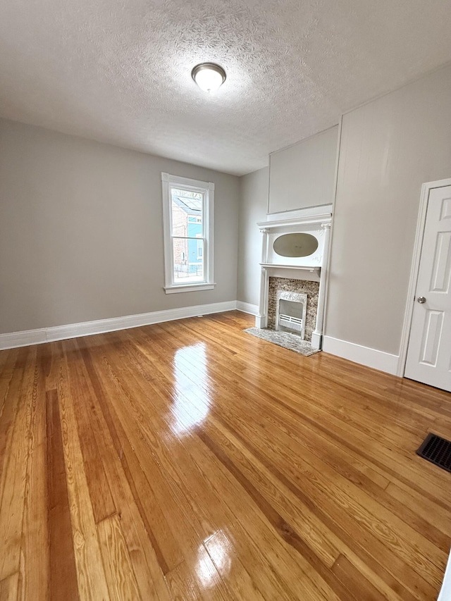 626 W 12th St, Covington, KY 41011 - unfurnished living room featuring light wood-style flooring, a textured ceiling, and a fireplace with flush hearth