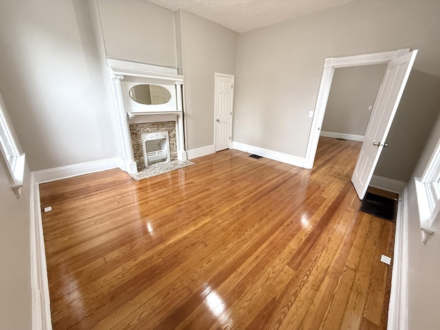 626 W 12th St, Covington, KY 41011 - unfurnished living room with wood finished floors and a fireplace with flush hearth