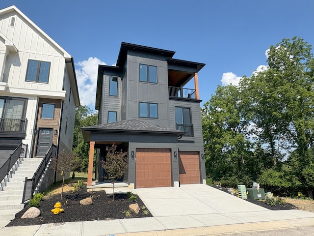 888 Belle Ridge Loop, Bellevue, KY 41073 - modern home featuring a balcony, an attached garage, driveway, stairs, and board and batten siding