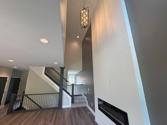 888 Belle Ridge Loop, Bellevue, KY 41073 - stairs featuring wood finished floors, a chandelier, recessed lighting, and a glass covered fireplace