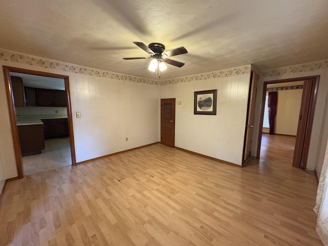 617 Woolery St, Falmouth, KY 41040 - unfurnished room featuring light wood-style flooring, ceiling fan, wallpapered walls, and a textured ceiling