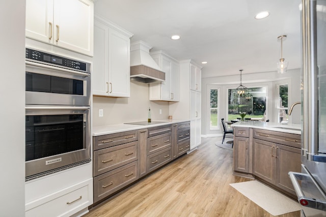 1312 Deer Hollow Ct, Hebron, KY 41048 - kitchen featuring stainless steel appliances, white cabinets, light wood-type flooring, light countertops, and pendant lighting