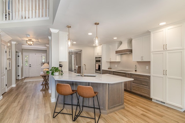 1312 Deer Hollow Ct, Hebron, KY 41048 - kitchen with custom exhaust hood, a kitchen bar, light wood-type flooring, white cabinetry, and a peninsula