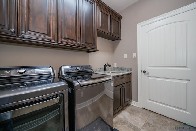 clothes washing area with cabinets, sink, light tile patterned flooring, and washing machine and clothes dryer