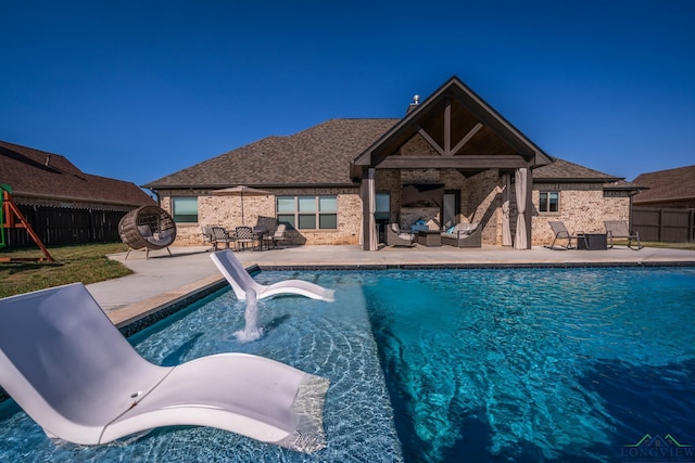 view of pool with exterior fireplace, a patio area, and a water slide