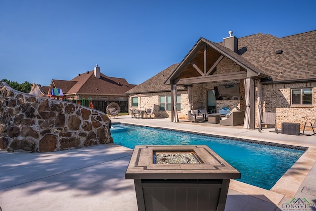 view of pool featuring an outdoor living space with a fireplace and a patio