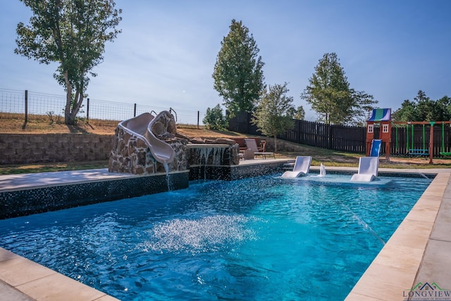 view of pool with a playground, pool water feature, and a water slide