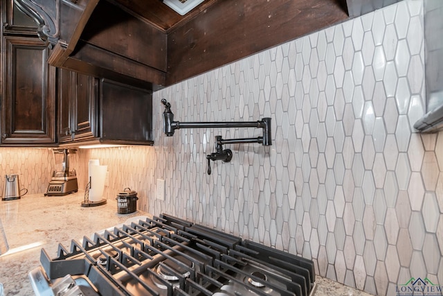 kitchen with light stone countertops, decorative backsplash, dark brown cabinetry, and cooktop