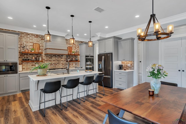 kitchen with visible vents, a center island with sink, gray cabinets, appliances with stainless steel finishes, and a notable chandelier