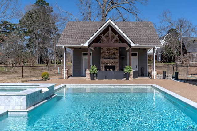 outdoor pool with an in ground hot tub, fence, an outdoor brick fireplace, and a patio area