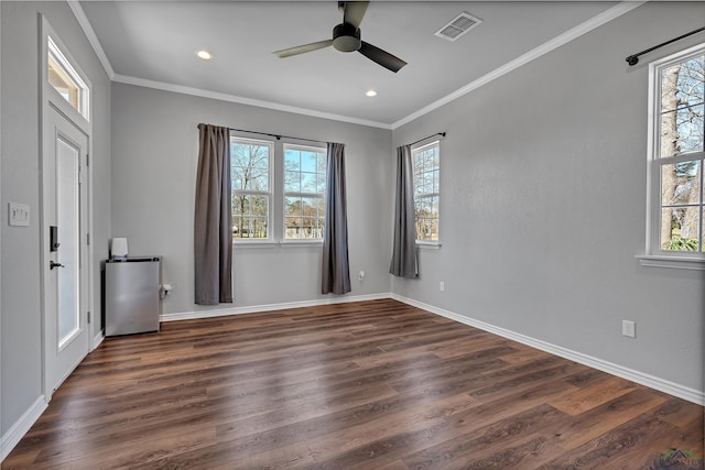 spare room with crown molding, visible vents, dark wood-style flooring, and ceiling fan