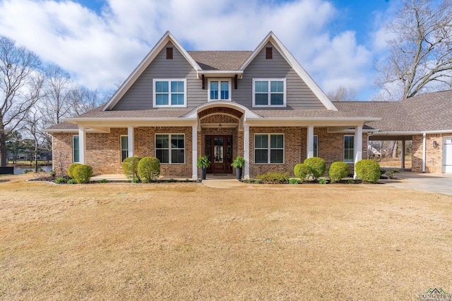 view of front of home featuring a front yard, brick siding, and roof with shingles