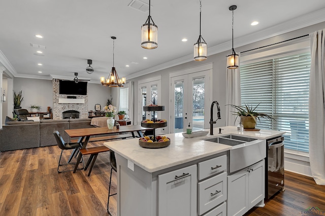 kitchen featuring a kitchen island with sink, visible vents, dark wood-type flooring, and a sink