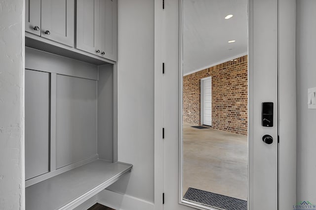 mudroom featuring recessed lighting and brick wall