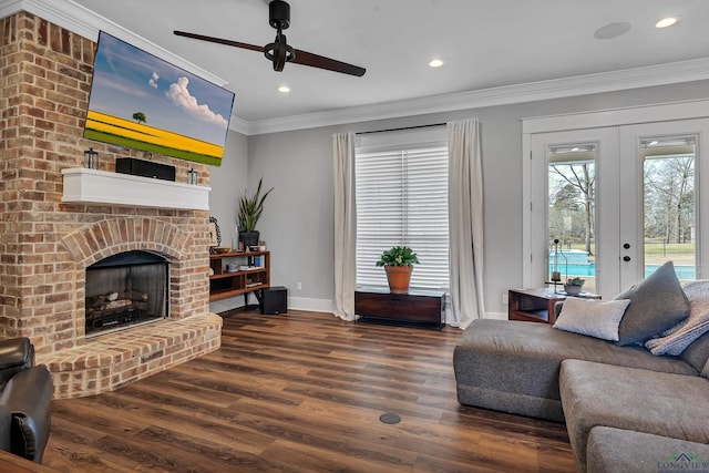 living room featuring wood finished floors, french doors, a fireplace, crown molding, and ceiling fan