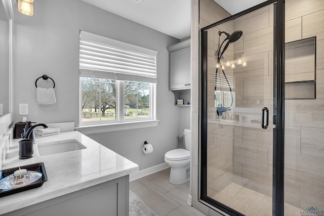 bathroom with baseboards, toilet, a shower stall, and vanity