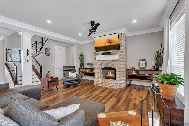 living room with crown molding, stairway, wood finished floors, and a fireplace