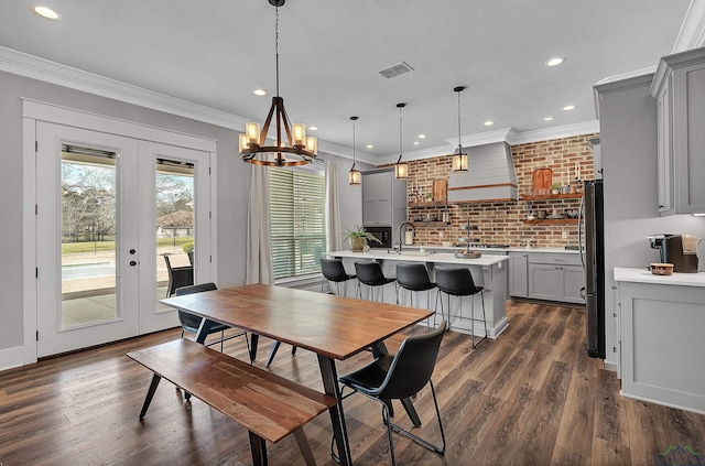 dining space with dark wood-style floors, visible vents, french doors, and ornamental molding