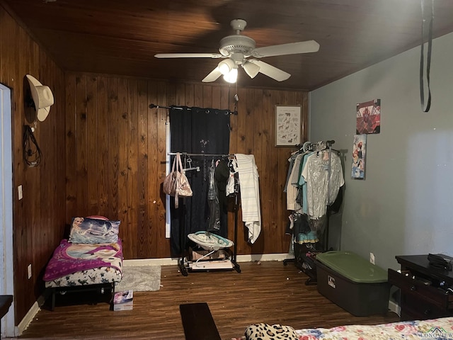 bedroom featuring dark hardwood / wood-style flooring, ceiling fan, and wooden walls