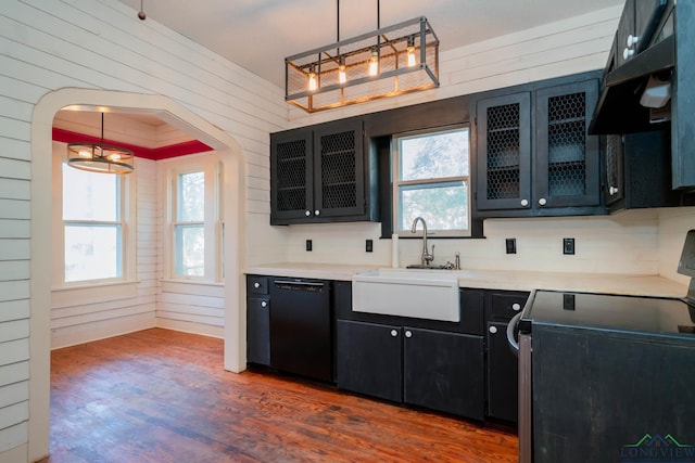 kitchen featuring pendant lighting, dishwasher, wood walls, sink, and range with electric cooktop