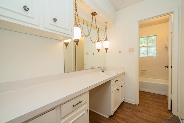 bathroom with hardwood / wood-style flooring, vanity, and tiled shower / bath