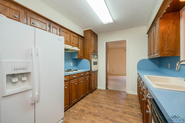 kitchen with white appliances, sink, hardwood / wood-style flooring, ornamental molding, and a textured ceiling