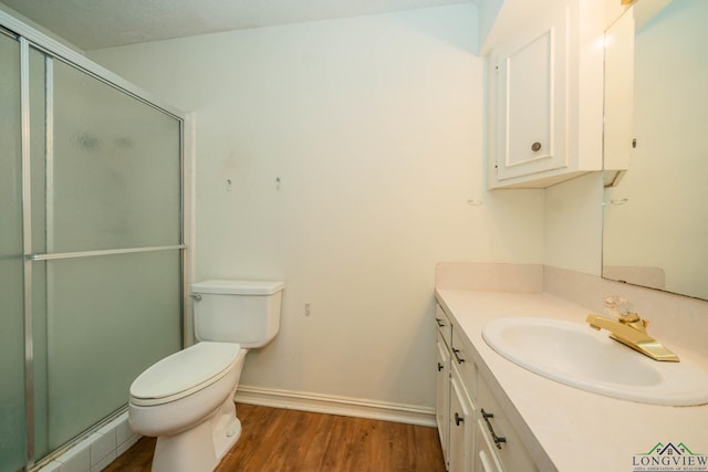 bathroom featuring hardwood / wood-style floors, vanity, a shower with door, toilet, and a textured ceiling