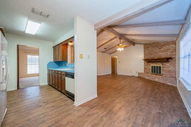 kitchen featuring a brick fireplace, a textured ceiling, ceiling fan, hardwood / wood-style flooring, and dishwasher