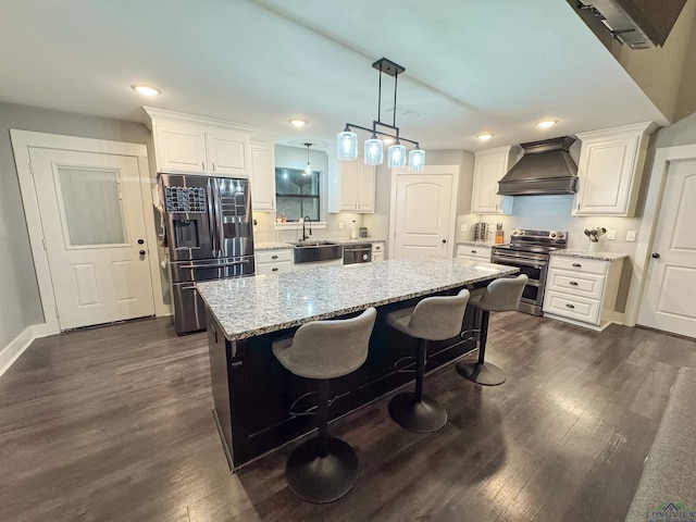 kitchen featuring premium range hood, a kitchen island, white cabinets, stainless steel appliances, and light stone countertops