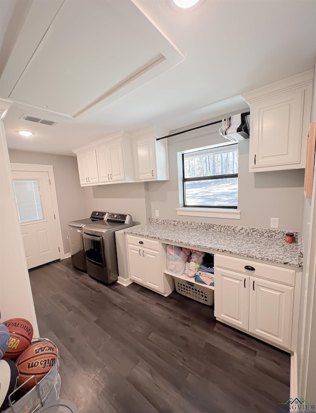 kitchen featuring light stone counters, dark hardwood / wood-style flooring, washing machine and dryer, and white cabinets