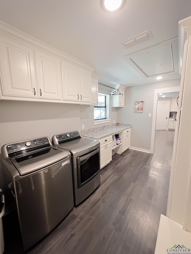 laundry area with dark wood-type flooring, cabinets, and washer and dryer