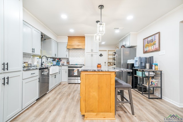 kitchen with a center island, stainless steel appliances, premium range hood, decorative light fixtures, and a breakfast bar