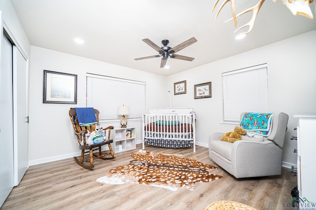 bedroom featuring hardwood / wood-style flooring, ceiling fan, a crib, and a closet