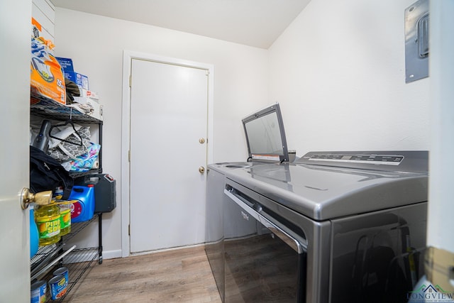 clothes washing area with light wood-type flooring and separate washer and dryer