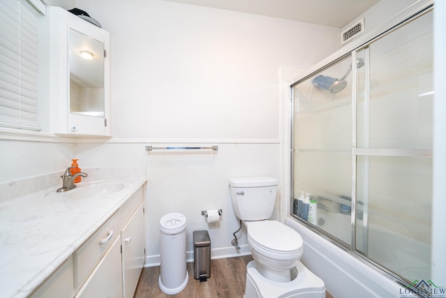 full bathroom featuring vanity, hardwood / wood-style flooring, toilet, and enclosed tub / shower combo