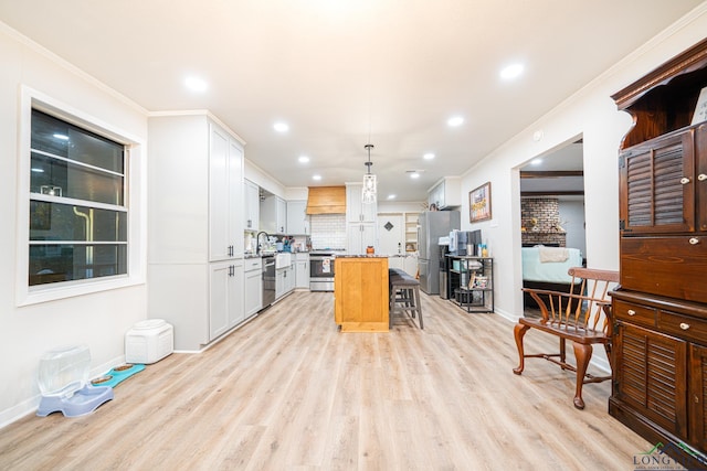 kitchen featuring a kitchen bar, stainless steel appliances, pendant lighting, a center island, and white cabinetry