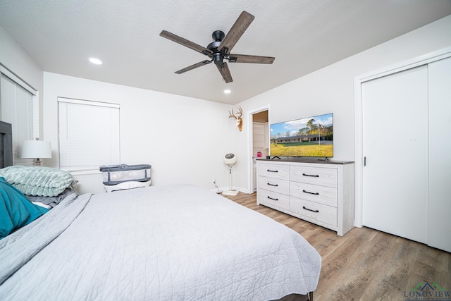 bedroom with ceiling fan, light hardwood / wood-style floors, and a textured ceiling