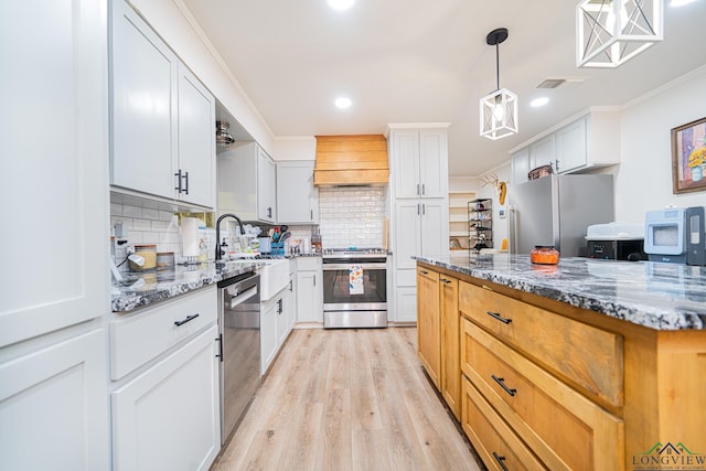 kitchen with appliances with stainless steel finishes, white cabinetry, custom range hood, and light stone counters