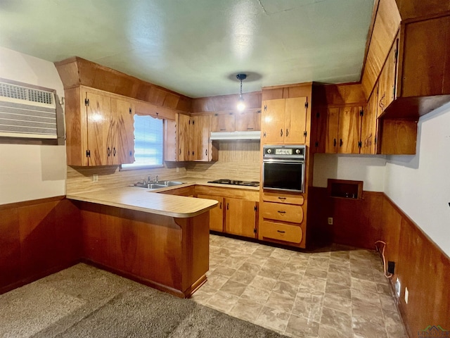 kitchen with pendant lighting, black appliances, an AC wall unit, sink, and kitchen peninsula