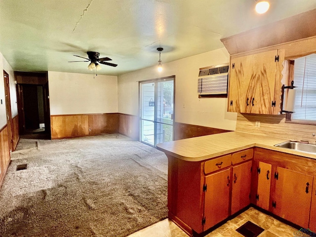 kitchen with wood walls, light carpet, sink, ceiling fan, and a wall mounted AC