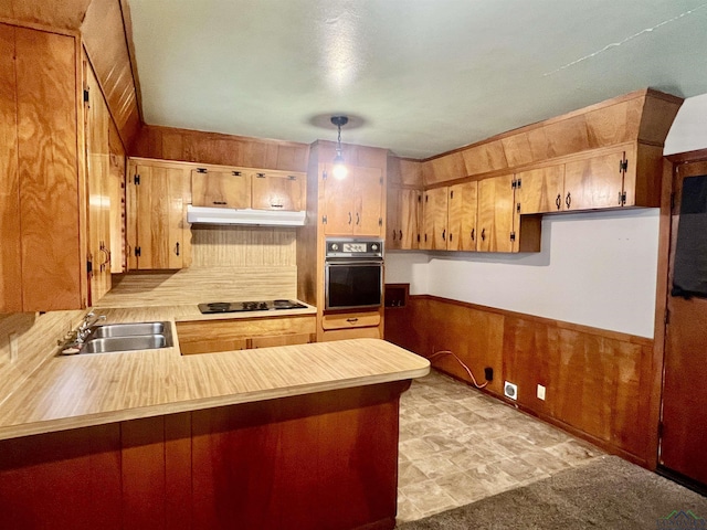 kitchen featuring sink, wooden walls, black oven, cooktop, and kitchen peninsula