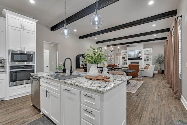 kitchen featuring a center island with sink, decorative light fixtures, sink, appliances with stainless steel finishes, and white cabinets