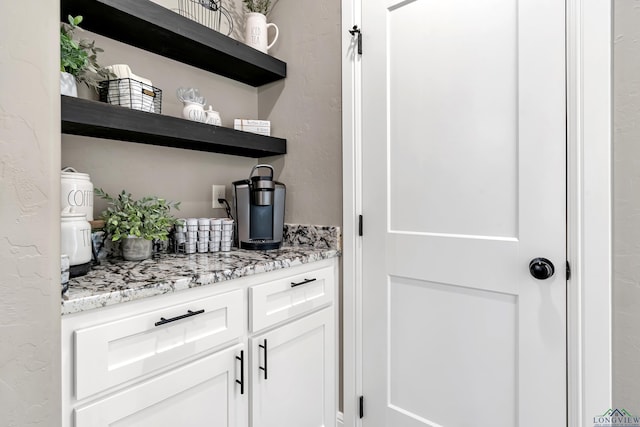 bar with white cabinetry and light stone counters