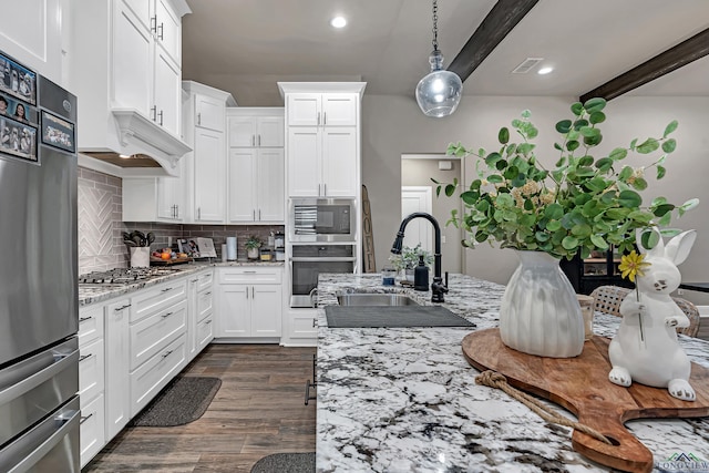 kitchen featuring sink, pendant lighting, stainless steel appliances, white cabinets, and light stone countertops