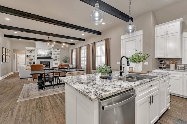 kitchen with dishwasher, light stone countertops, white cabinets, sink, and a kitchen island with sink