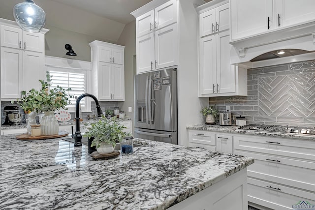 kitchen with appliances with stainless steel finishes, custom range hood, white cabinets, and backsplash