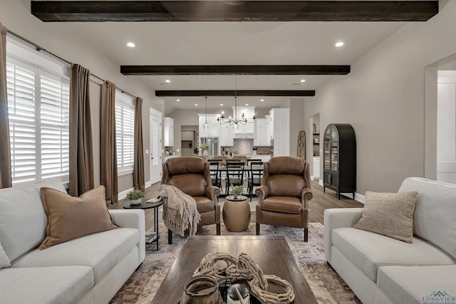 living room with beam ceiling, light hardwood / wood-style floors, and an inviting chandelier